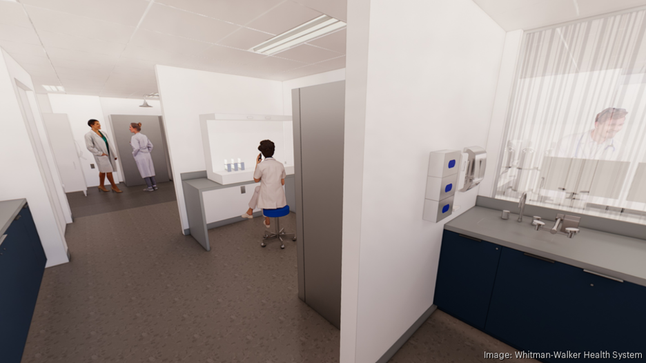 Three people in lab coats are in a clinical laboratory; one is seated at a workstation, while two are standing and talking near a doorway. Laboratory equipment is visible on counters.