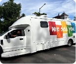 A white mobile clinic van with a colorful graphic on the side that reads “we see you.”