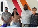 Four people standing together in front of a white surface with orange and red stripes.