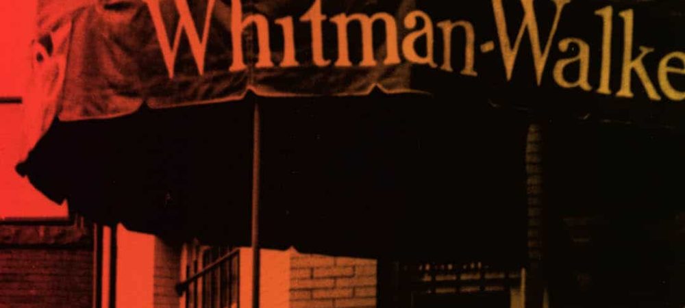 A red-tinted photo shows part of an awning with the text "Whitman-Walker" above a building with brick walls and a window.