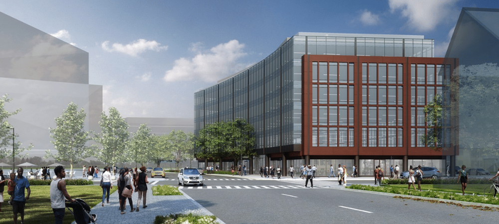 A modern office building with glass windows and a red-brown facade, surrounded by trees, people walking, and cars on a sunny day.