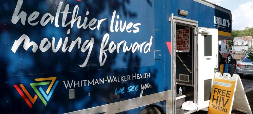 A Whitman-Walker Health mobile clinic with the slogan "healthier lives moving forward" offers free HIV testing, as indicated by a sign outside the vehicle.