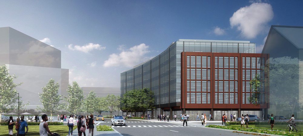 A modern multi-story office building with large windows sits at a street corner as people walk on sidewalks and cross the road under a sunny sky.