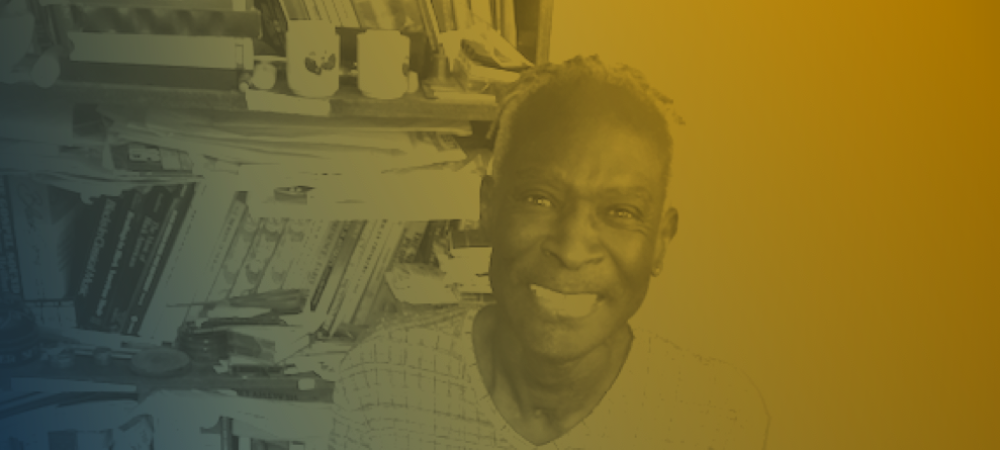 A person smiling in front of a cluttered bookshelf, with a yellow and blue gradient overlay on the image.